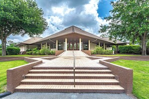 A building with a central staircase leading to a covered entrance, surrounded by greenery and a clear sky. - Cozy Shipyard Retreat| 2BR, Patio, Beach Parking & Golf Course Views (Hilton Head Island)