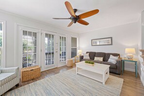 A living room with a ceiling fan, a sofa, a coffee table, and a wicker basket.