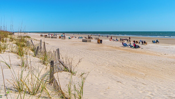 Une plage avec des dunes de sable, des chaises de plage et des parasols.