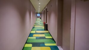 A long, narrow hallway with a colorful patterned carpet, beige walls, and doors on one side. - Vatica Hotel Wuxi Yixing Renmin Road (Wuxi)