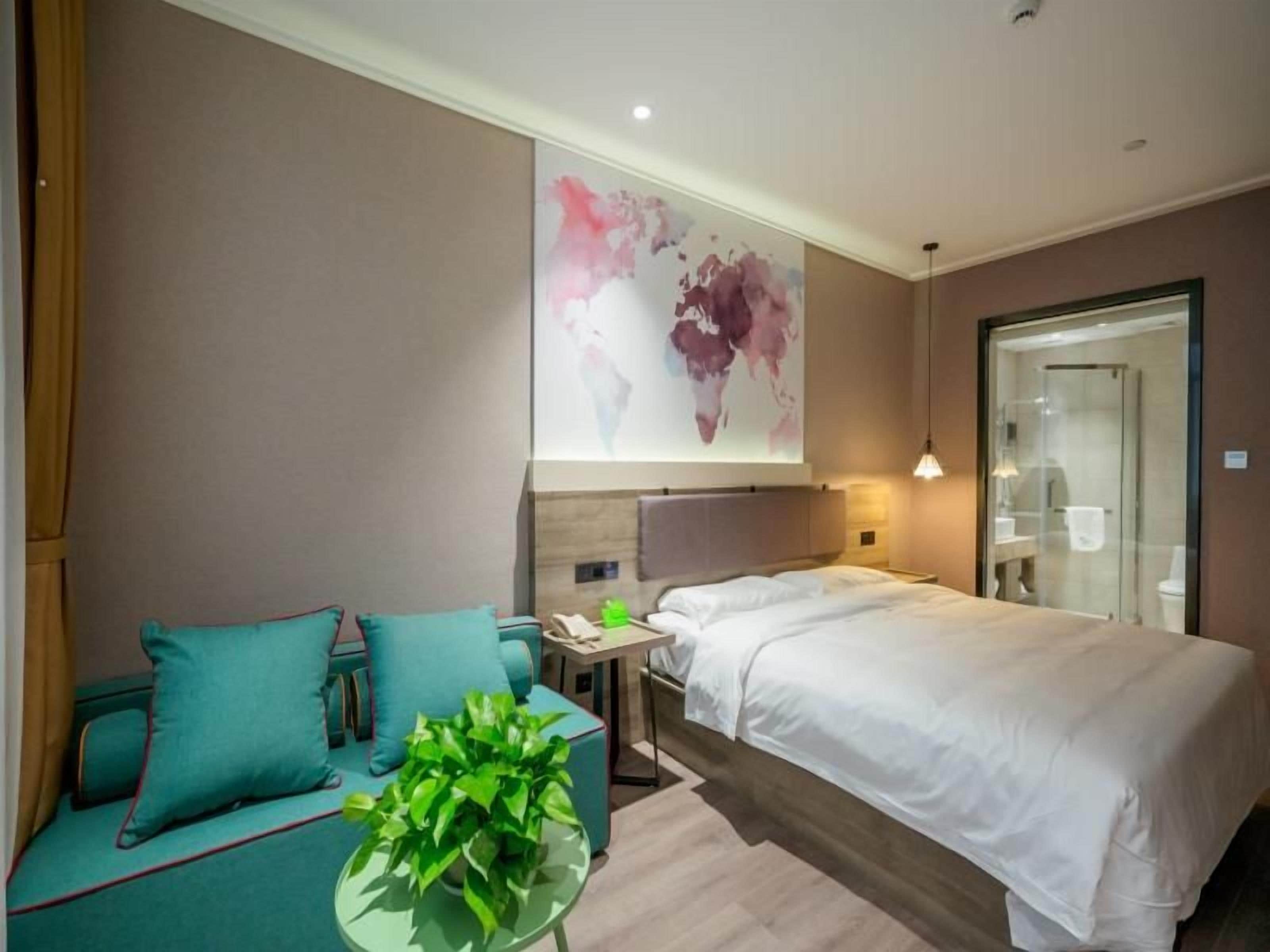 Une chambre d’hôtel comprenant un lit, un coin salon avec une table et une grande peinture abstraite accrochée au mur.