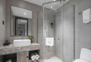 A modern bathroom with a glass-enclosed shower, a white sink, and a towel rack. - Vatica Hotel Wuxi Yixing Renmin Road (Wuxi)