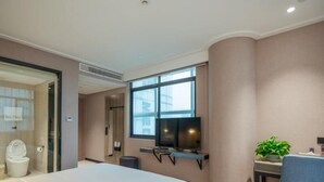 A hotel room with a bed, a desk with a chair, a television, and a window. - Vatica Hotel Wuxi Yixing Renmin Road (Wuxi)
