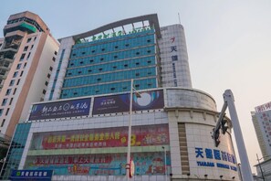 Un edificio de varios pisos con una fachada azul destacada, ventanas amplias y varios anuncios.
