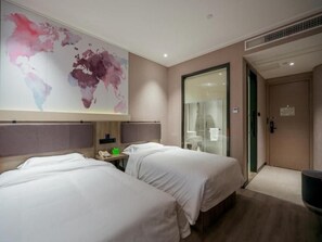 Habitación de hotel con dos camas, un mapa mundial en la pared, una puerta de cristal y un televisor de pantalla plana.