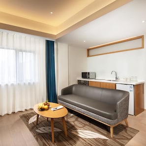 A modern hotel room with a sofa, a small table with fruits, a microwave, and a sink. - Holiday Inn Shanghai Hongqiao Central (Shanghai)