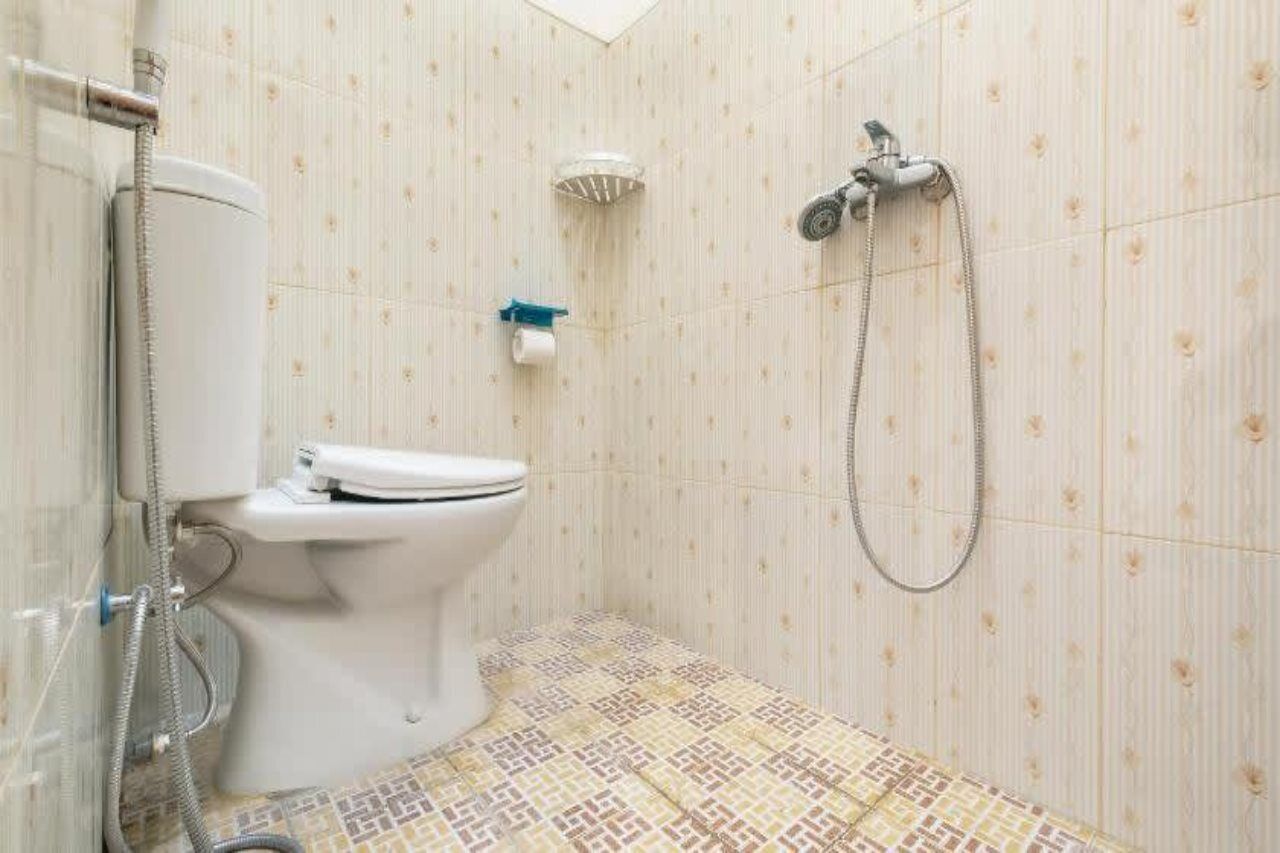A small bathroom with a toilet, a shower, and a toilet paper holder on the wall.