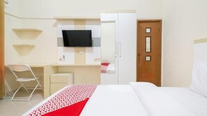 Une chambre d’hôtel équipée d’un lit, d’un bureau, d’une chaise, d’un téléviseur fixé au mur et d’une armoire.