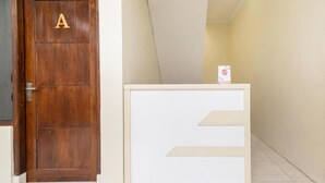 Une porte en bois ornée d’un « A », un comptoir d’accueil aux couleurs blanc et beige, et un mur sobre.