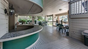 A covered outdoor area with a curved counter, outdoor seating, and a view of the surrounding greenery.