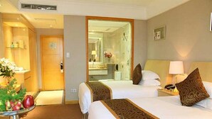 A hotel room with two beds, a bedside table with a lamp, a mirror, and a fruit bowl on the side. - Jinling Huifu Hotel (Yangzhou)