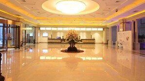 A spacious lobby with a central reception desk, a large circular light fixture on the ceiling, and a polished floor reflecting the surroundings. - Jinling Huifu Hotel (Yangzhou)
