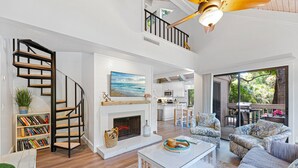 A spacious living area with a fireplace, a staircase, a dining area, and a view of the outdoors.