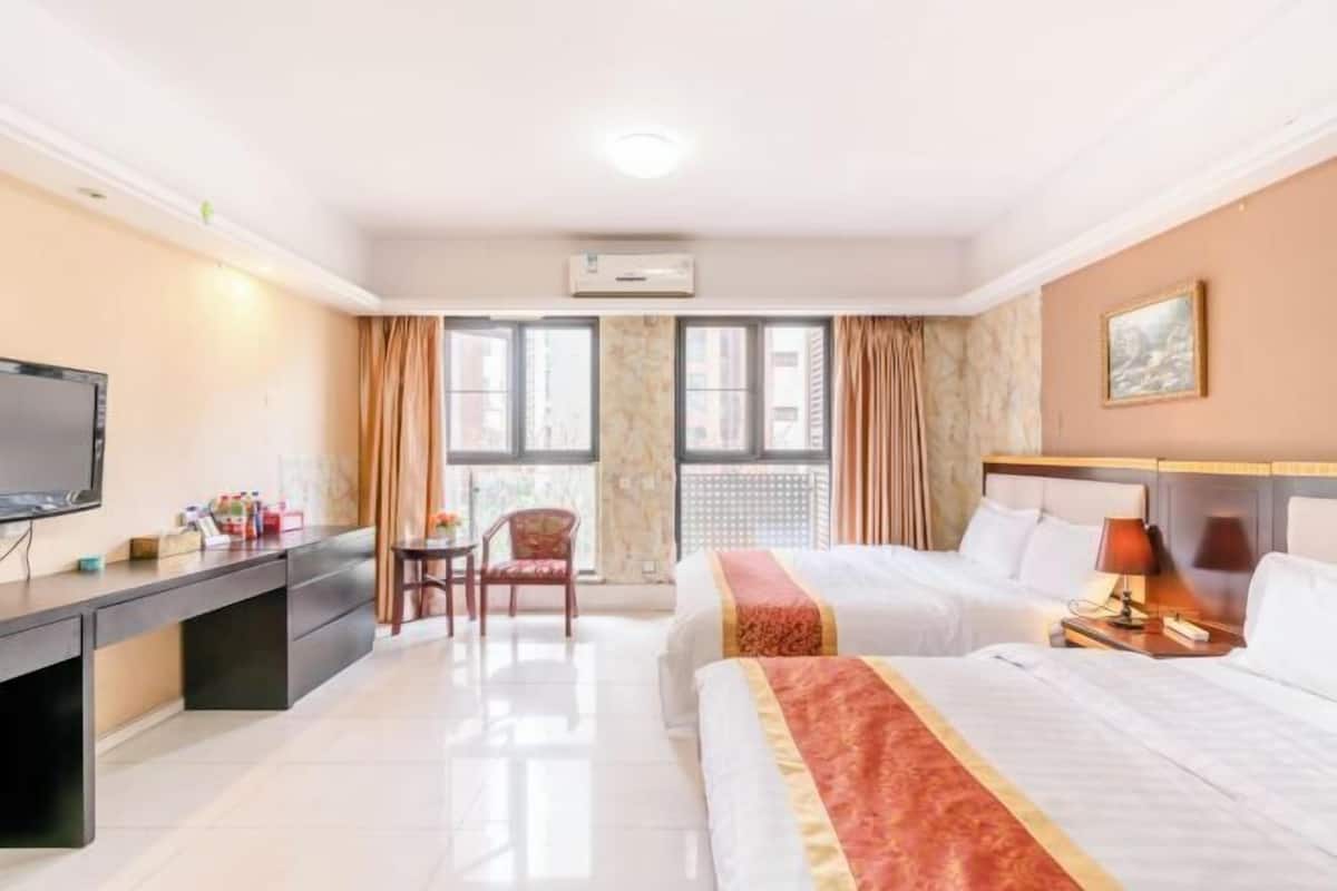Une chambre d’hôtel équipée d’un lit, d’un bureau, d’une chaise, d’une télévision et d’une fenêtre avec des rideaux.