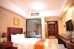 A hotel room with a bed, bedside tables, a television, and a mirror.