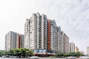 A multi-story residential building with balconies, a central commercial area, and a clear sky. - Shidai Weigang Business Hotel (Chengdu)