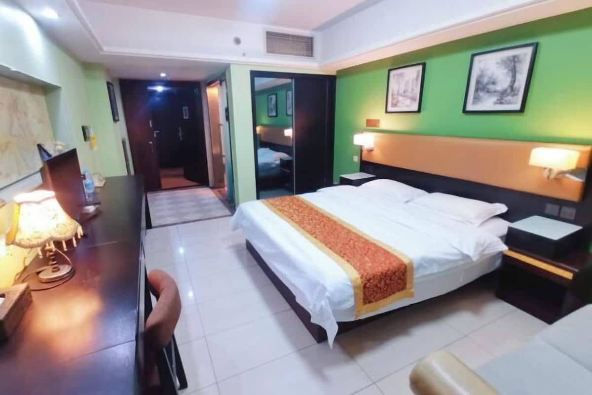 Une chambre d’hôtel comprenant un lit, des tables de chevet, un bureau avec une lampe et une chaise.