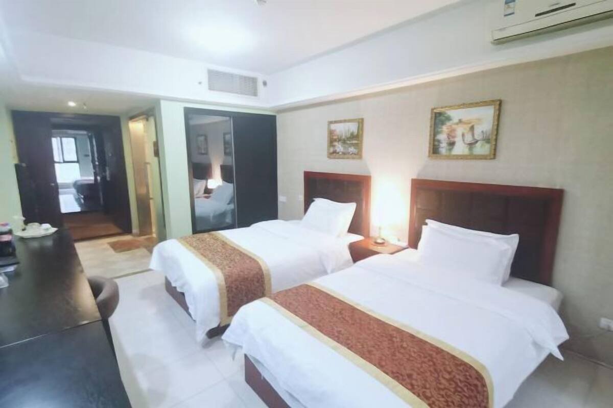 Une chambre d’hôtel avec deux lits, un bureau et un miroir.
