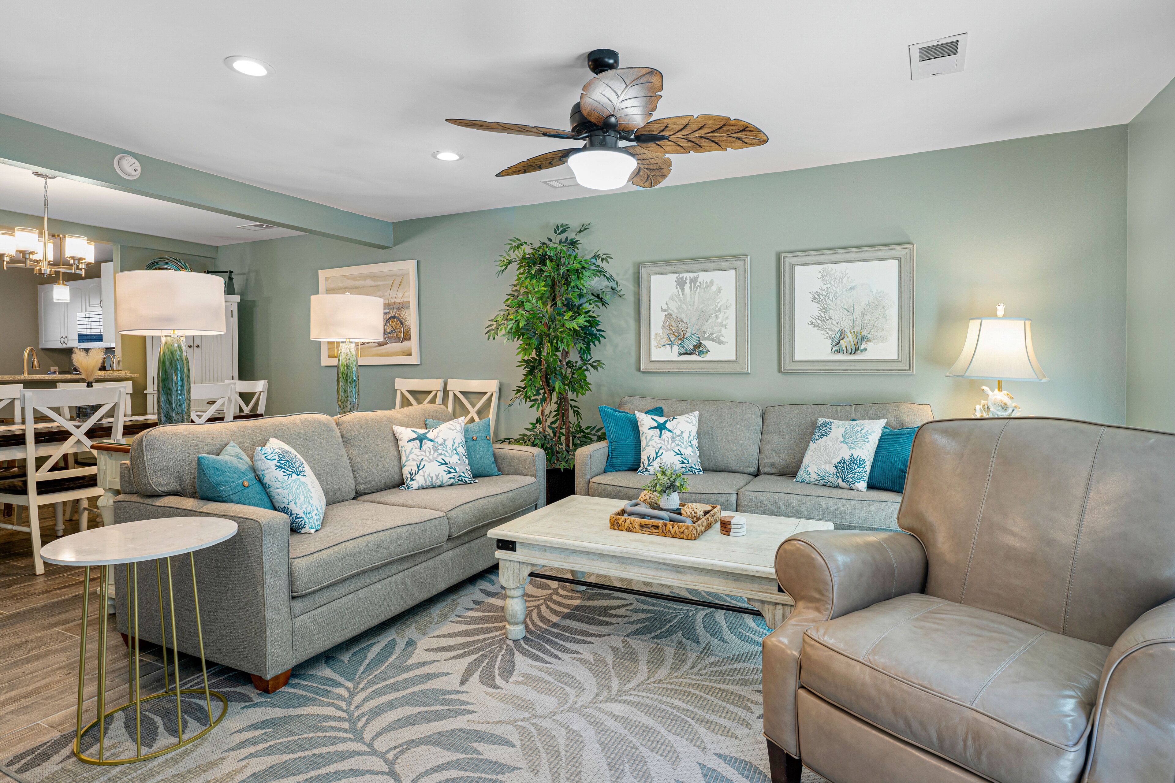 A living room with a sofa, armchairs, a coffee table, and a ceiling fan.