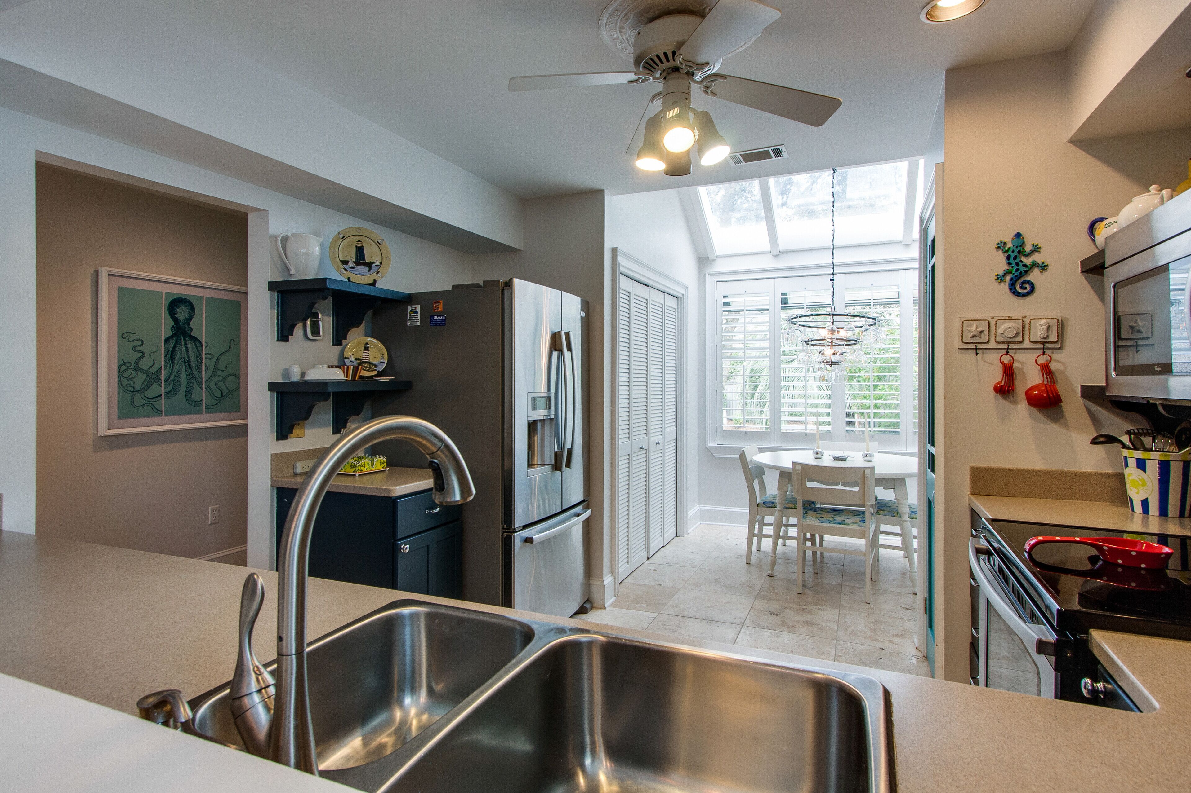 A modern kitchen with a stainless steel sink, a refrigerator, and a ceiling fan.