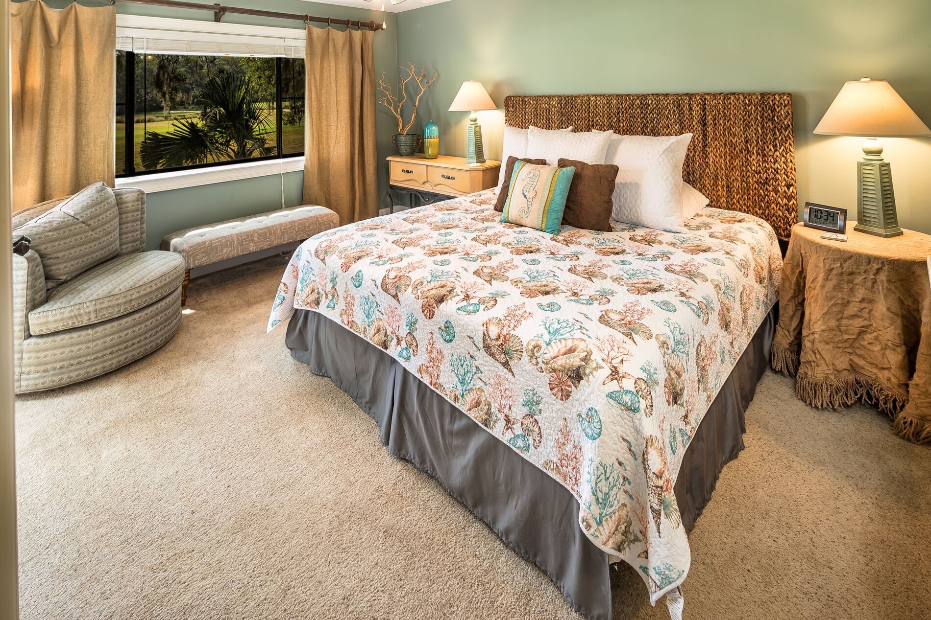 Quarto com uma cama grande, uma cadeira, uma mesa de cabeceira e vista para o exterior.