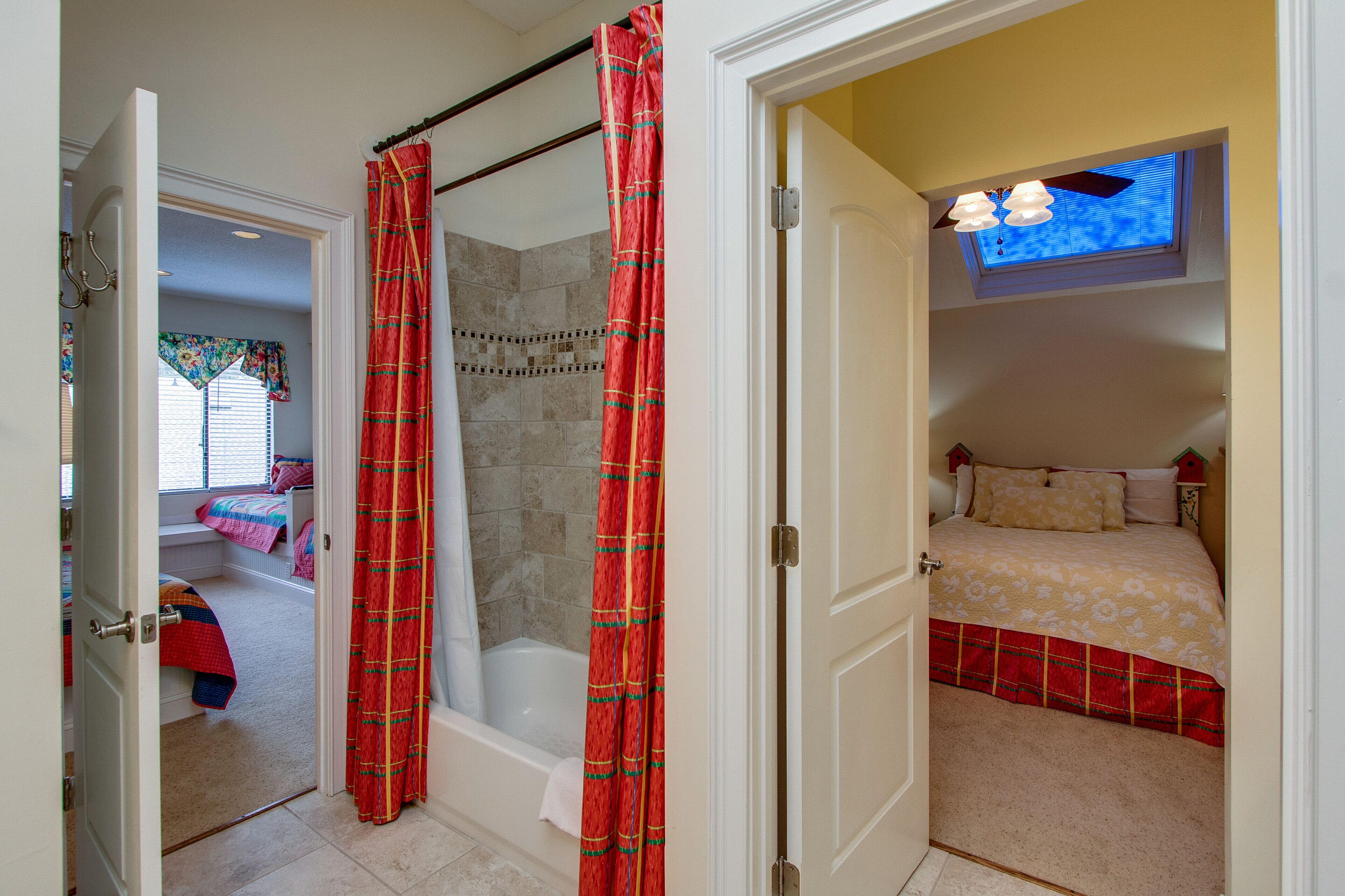 Un baño con ducha, bañera y retrete. Cuenta con una ventana con persianas y cortina.