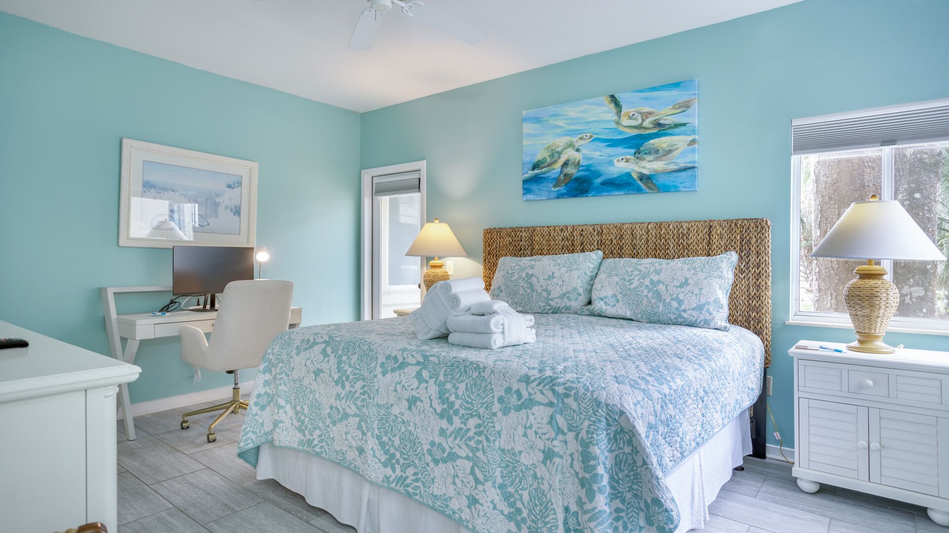 Une chambre à coucher avec un lit, un bureau, une chaise, une lampe et un tableau au mur.