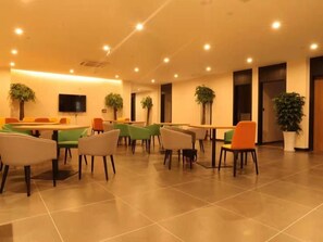 A spacious indoor area with multiple tables and chairs, a flat-screen TV mounted on the wall, and potted plants. - Greentree Inn Lanzhou Zhongchuan Airport (Lanzhou)