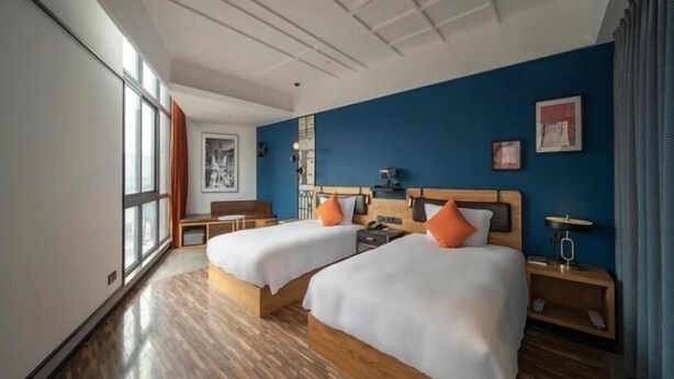 A hotel room with two beds, wooden flooring, a large window, and a blue accent wall. - Greentree Inn Lanzhou Zhongchuan Airport (Lanzhou)