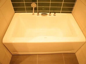 A rectangular bathtub with a faucet and a handheld showerhead, set against a tiled wall. - Greentree Inn Lanzhou Zhongchuan Airport (Lanzhou)