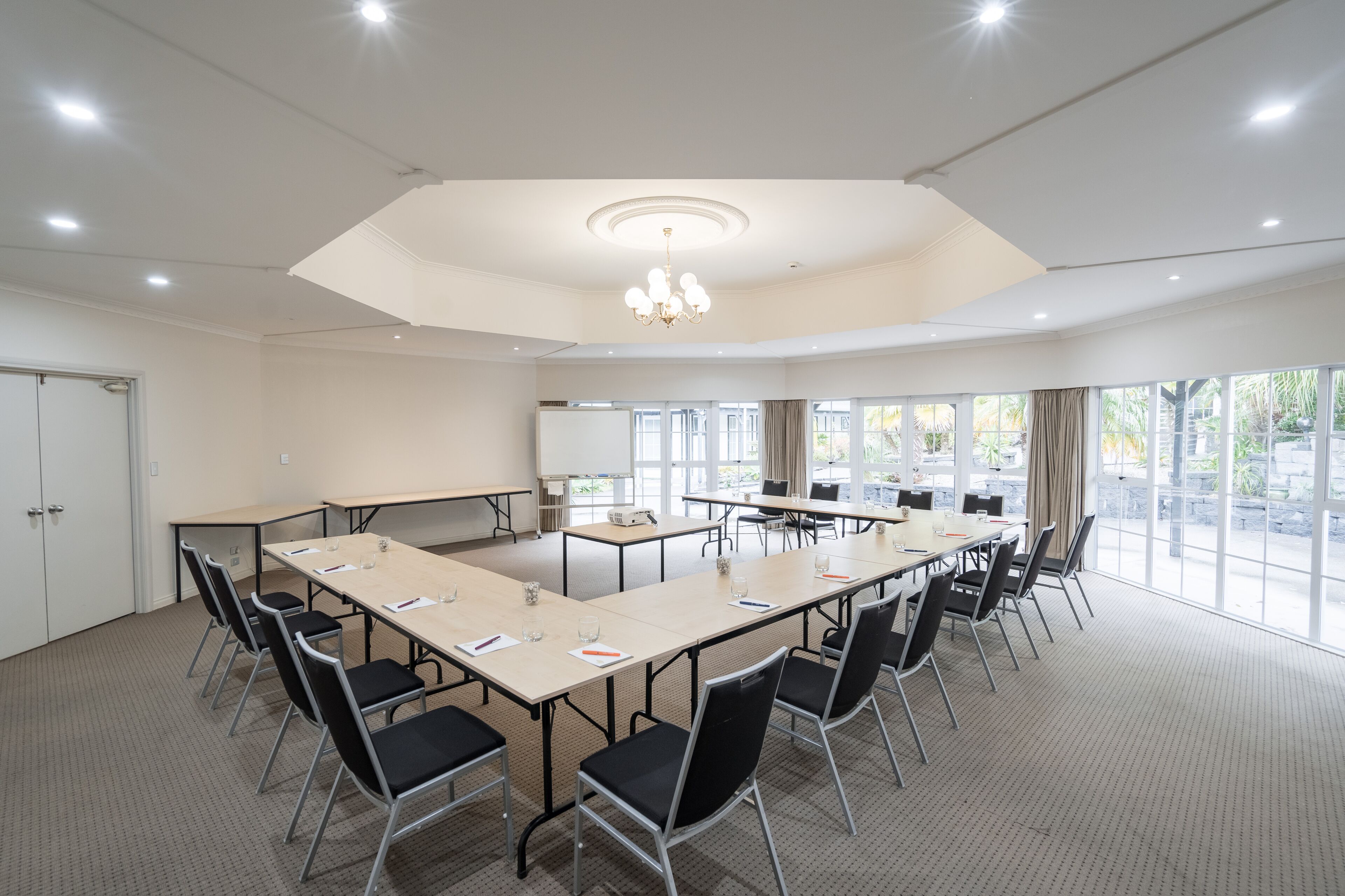 Une salle de conférence dotée d’une grande table ovale, de nombreuses chaises, d’un projecteur et d’un tableau blanc.