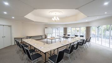 Une salle de conférence dotée d’une grande table ovale, de nombreuses chaises, d’un projecteur et d’un tableau blanc.