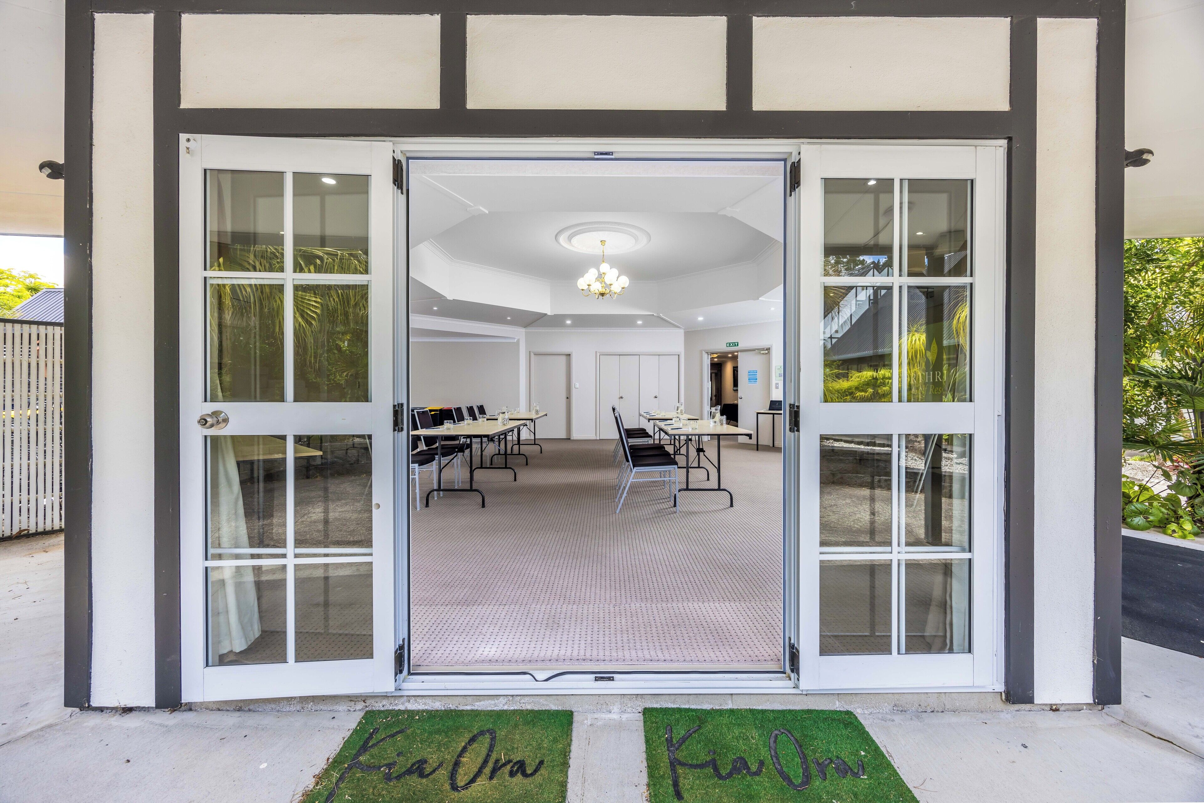 A conference room with a large table and chairs, a ceiling light, and a door with glass panels.