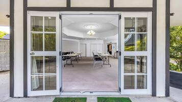 A conference room with a large table and chairs, a ceiling light, and a door with glass panels.