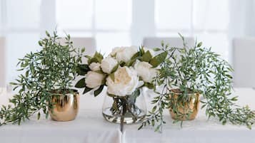 A table with three gold vases containing white flowers and green foliage.