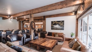 Een ruime woonkamer met leren banken, een houten salontafel en een groot raam.