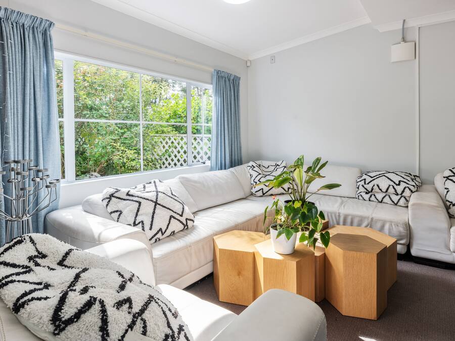 Uma sala de estar moderna com um sofá branco, uma mesa de centro de madeira e uma planta em vaso.