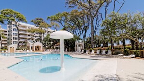 A swimming pool with lounge chairs and a distinctive mushroom-shaped fountain.