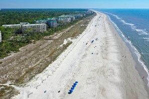 Un resort sulla spiaggia con diversi edifici, una spiaggia sabbiosa e vista sull'oceano.