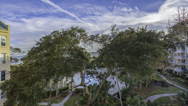 A residential area with a pool, pathways, and a view of the ocean.