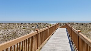 A wooden boardwalk leading to the beach with a clear view of the ocean.