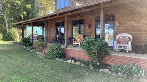 Une maison en bois avec un porche couvert, un espace salon extérieur et un mur en briques.