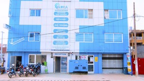 A hotel with a blue and white facade, a reception area, and several motorcycles parked outside. - Nora Hotel (Cotonou)