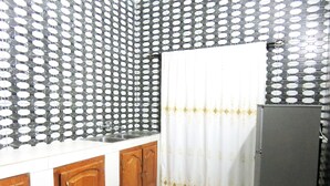 A kitchen with a sink, wooden cabinets, a patterned backsplash, and a checkered floor. - Nora Hotel (Cotonou)