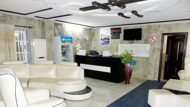 A reception area with a reception desk, a sofa, a coffee table, and a decorative vase. - Nora Hotel (Cotonou)