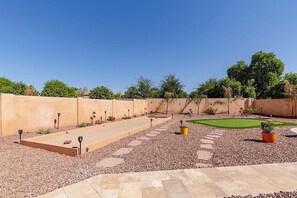 A well-maintained outdoor area with a putting green, a stone pathway, and a variety of plants and flowers. - Westgate Wonder ~ A Resort-Style Oasis w/ Heated Pool, Spa, Game Rooms, Putting Green & More! (Glendale)