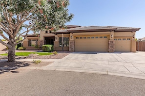 A two-story house with a garage, a driveway, and a tree in the front yard. - Westgate Wonder ~ A Resort-Style Oasis w/ Heated Pool, Spa, Game Rooms, Putting Green & More! (Glendale)