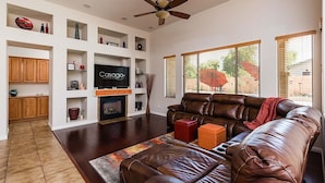 A spacious living room with a leather sofa, a fireplace, and a television displaying 'Casago Luxury Properties'. - Westgate Wonder ~ A Resort-Style Oasis w/ Heated Pool, Spa, Game Rooms, Putting Green & More! (Glendale)