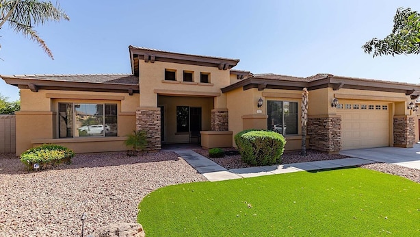 A two-story house with a garage, a front yard with a lawn and a rock garden, and a small tree. - Westgate Wonder ~ A Resort-Style Oasis w/ Heated Pool, Spa, Game Rooms, Putting Green & More! (Glendale)