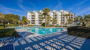 Ein Hotel mit Swimmingpool, Palmen und blauem Himmel.